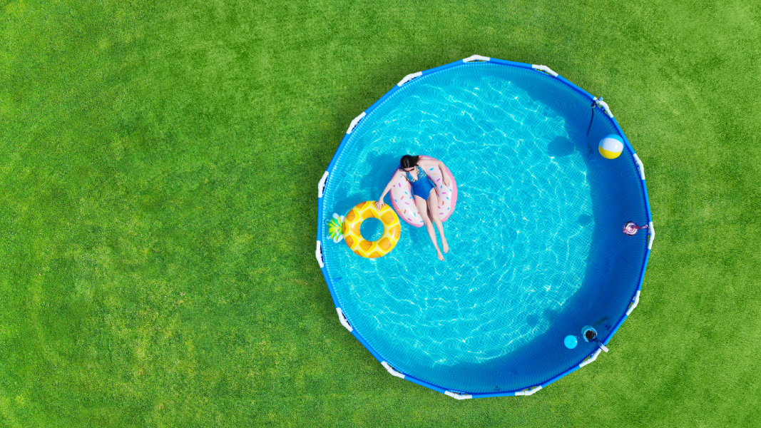 Kobieta pływa w basenie stelażowym który stoi w ogrodzie
